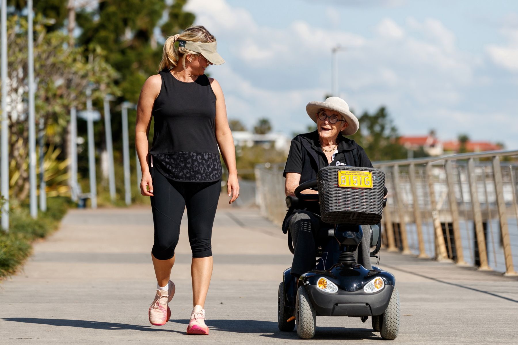 Woman walking and older woman rolling using her motorised wheelchair