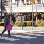 lady crossing a pedestrian crossing with a pink shopping bag