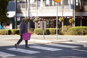 lady crossing a pedestrian crossing with a pink shopping bag