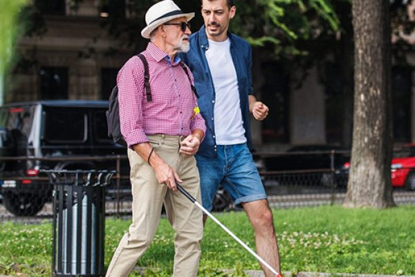 Image of two men walking, one has a white cane